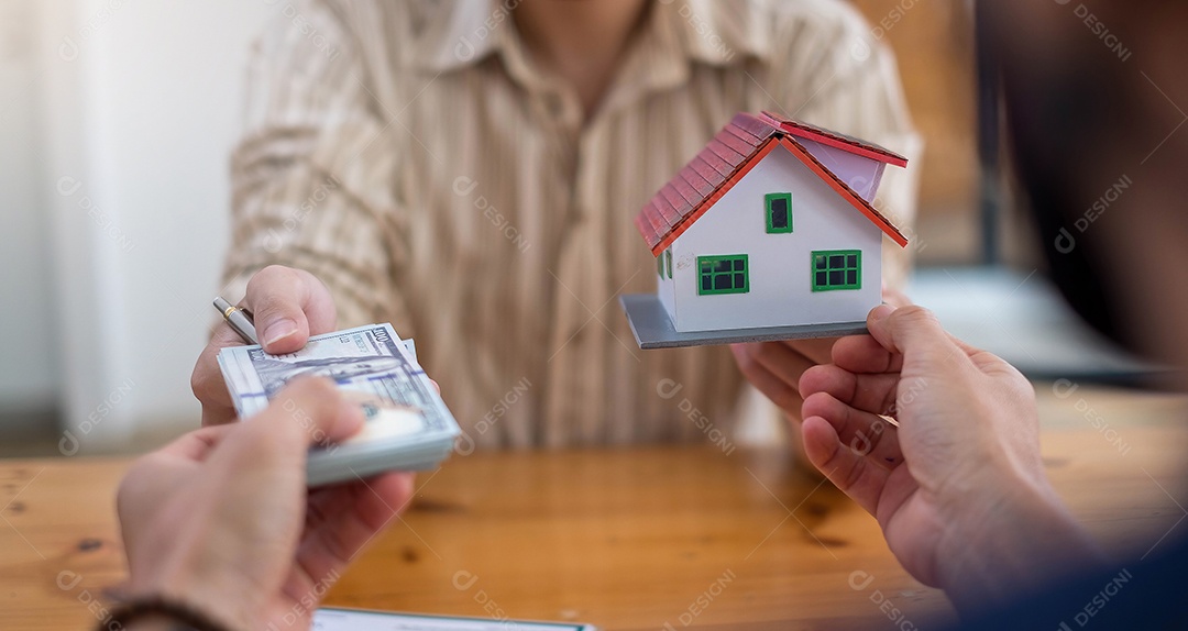 Empresários entregando dólares com modelo de casa decorativa