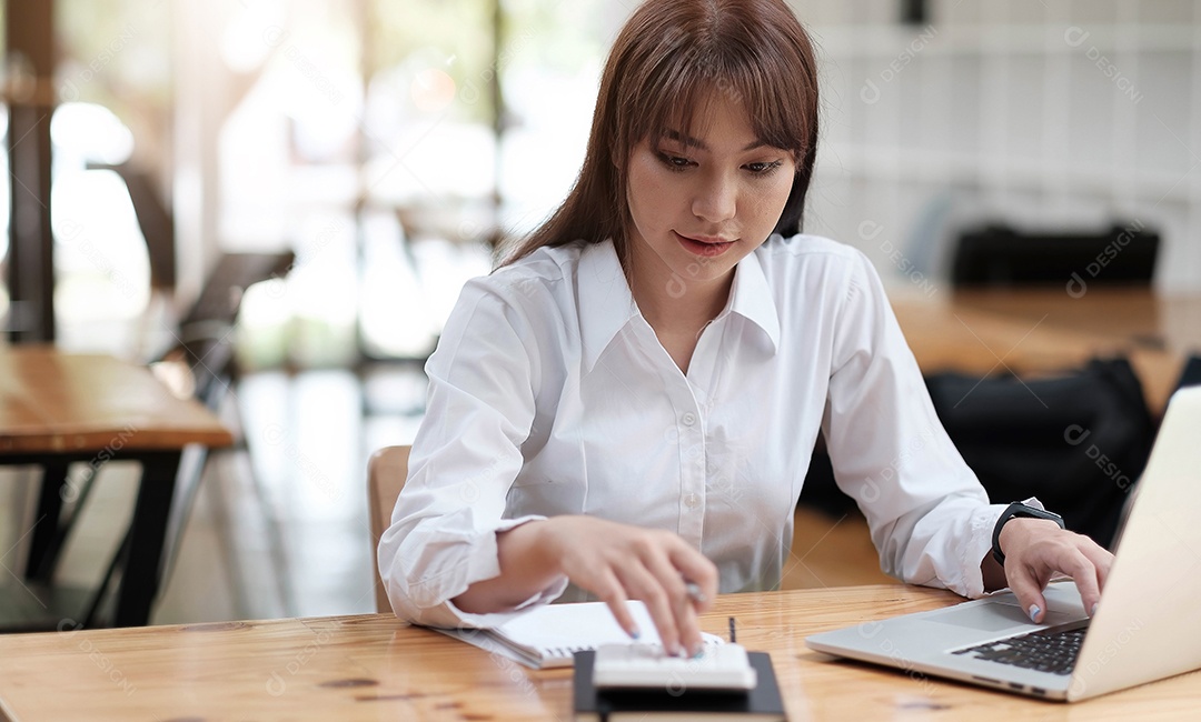 Uma jovem feliz senta-se à mesa, olha para a tela do laptop