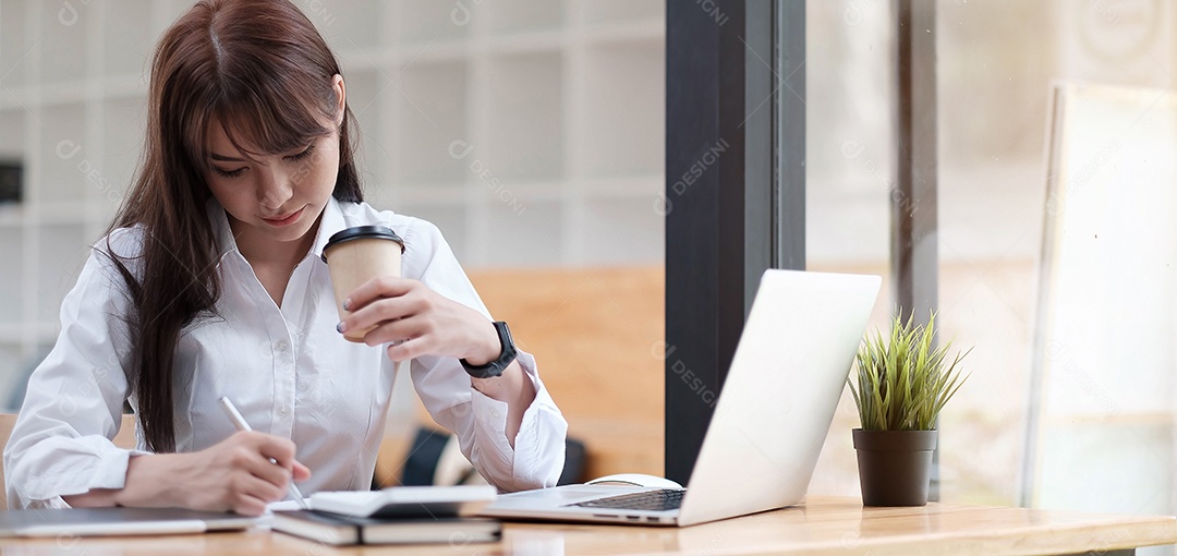 Mulher tomando chá, sentada na cadeira de um escritório, escrevendo