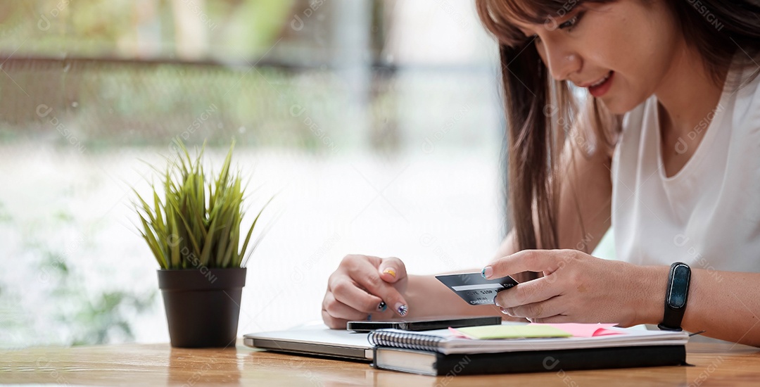 Mulher sorridente usa telefone celular para fazer compras online com cartão de crédito