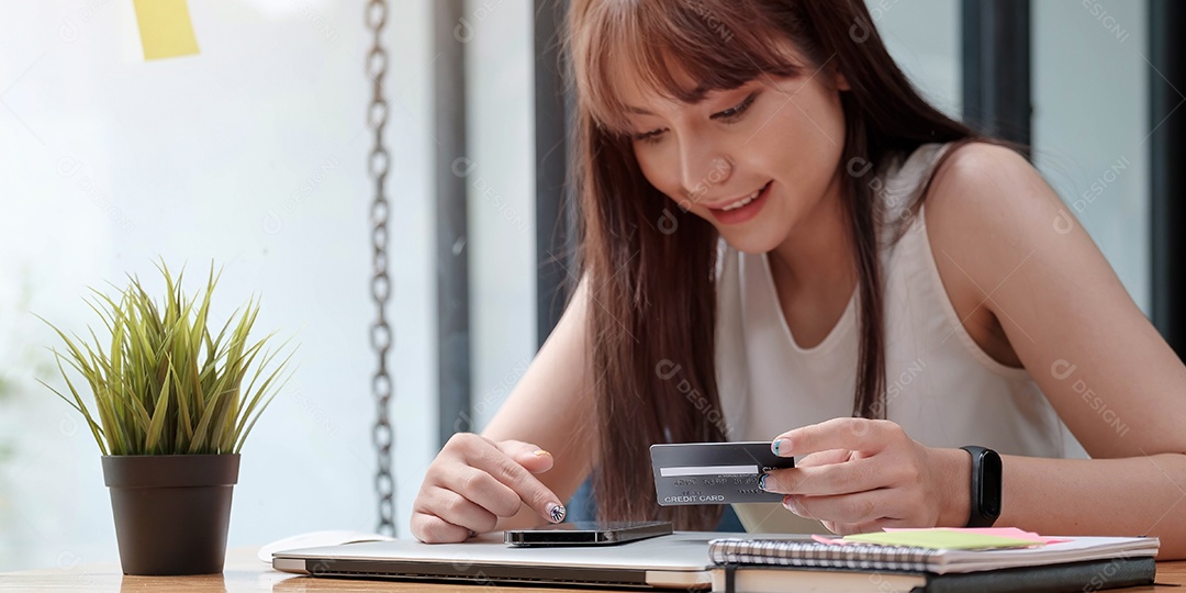 Mulher sorridente usa telefone celular para fazer compras online com cartão de crédito