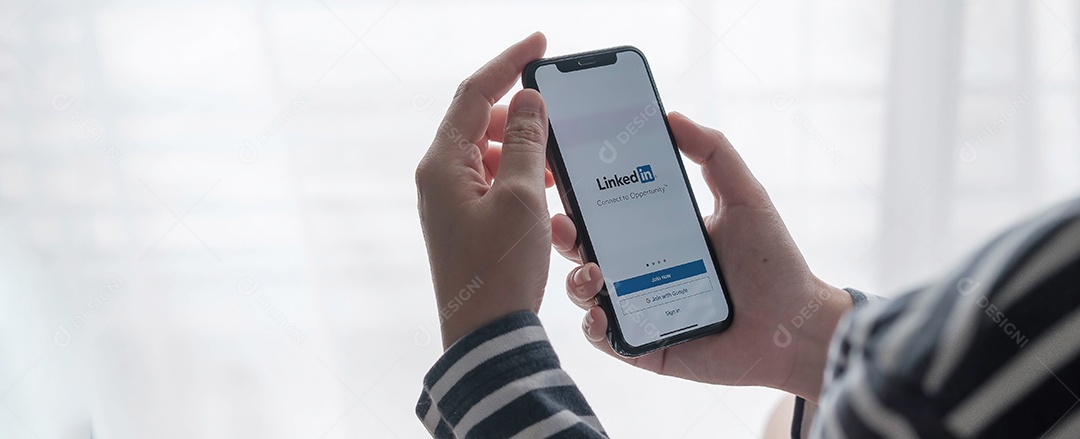 Uma mulher segura o Apple iPhone Xs com o aplicativo LinkedIn na tela.