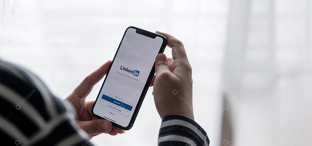 Uma mulher segura o Apple iPhone Xs com o aplicativo LinkedIn na tela.