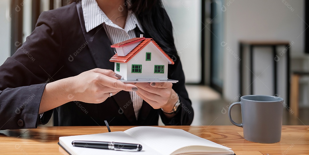 Mãos de uma jovem segurando um modelo casa.