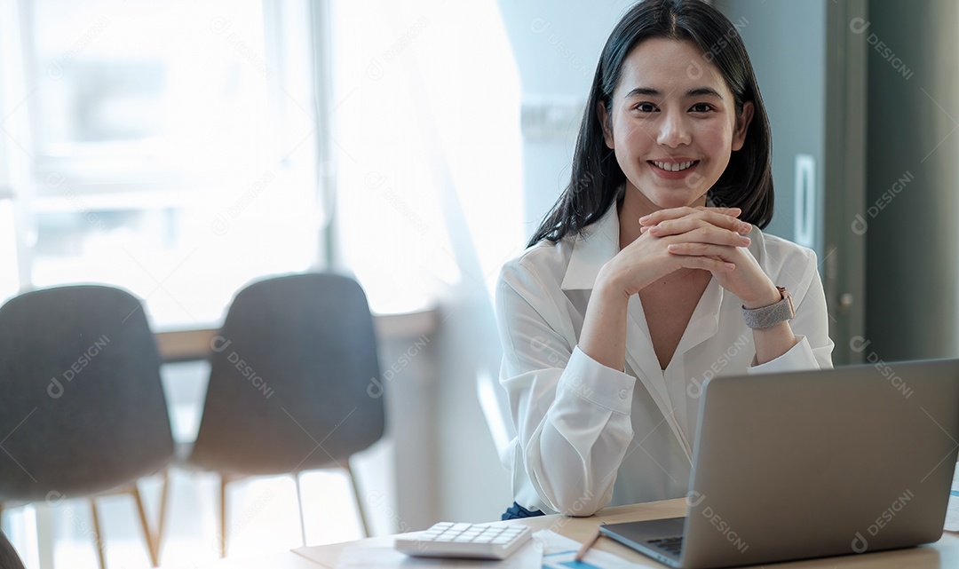 Linda jovem asiática trabalhando em um espaço de escritório com um laptop