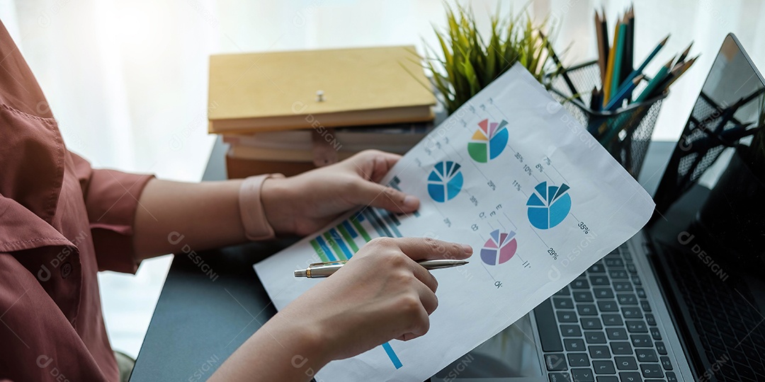 Mão segurando a caneta apontando no gráfico de relatório resumido e cálculo