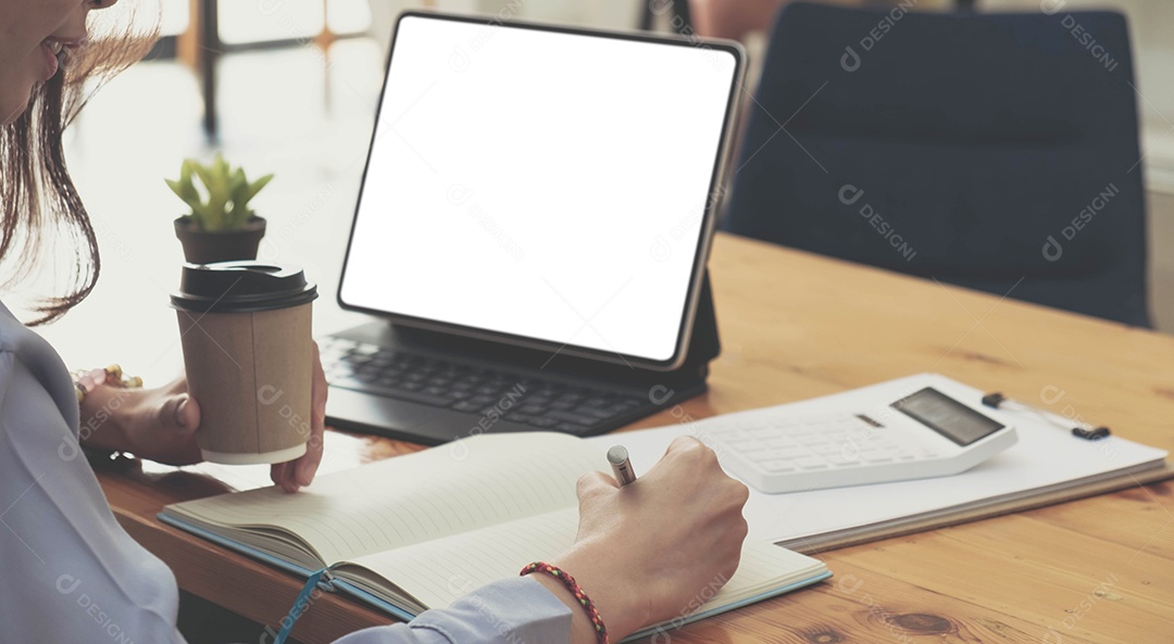 Menina sentada no computador de mesa, segurando o café e escrevendo o diário