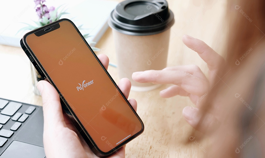 Payoneer App com artigos de papelaria em uma mesa de madeira marrom.