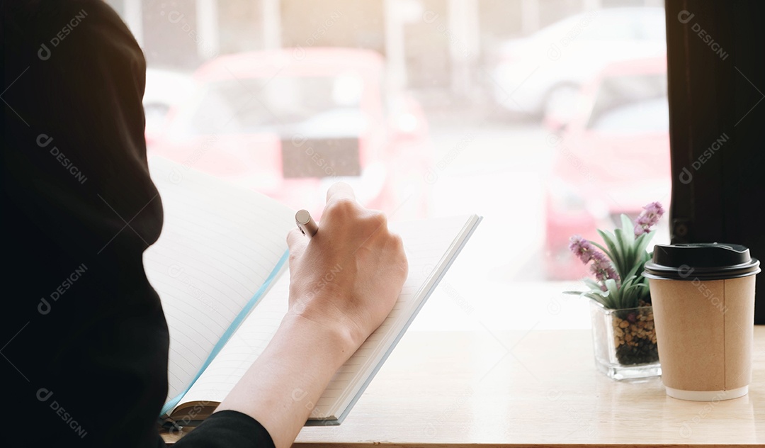 Mão de mulher de negócios trabalhando em um computador e escrevendo em um bloco de notas