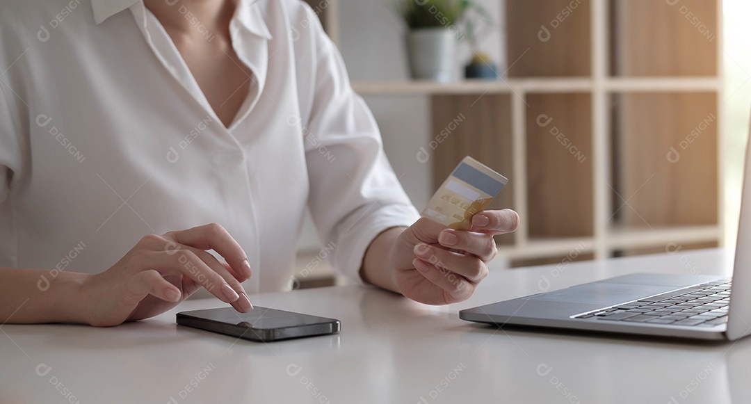 Jovem mulher segurando cartão de crédito e usando laptop