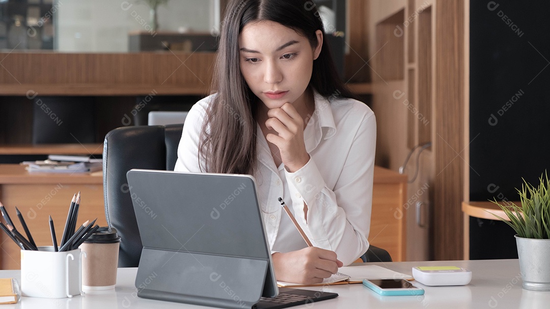 Mulher asiática anotando notas segurando um tablet para análise de dados