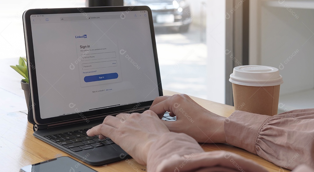 Mulher usando computador olhando a página de login do LinkedIn na tela do laptop.