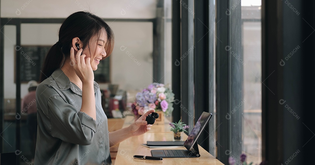 Jovem asiática usa fones de ouvido sem fio para ter cursos de idiomas on-line