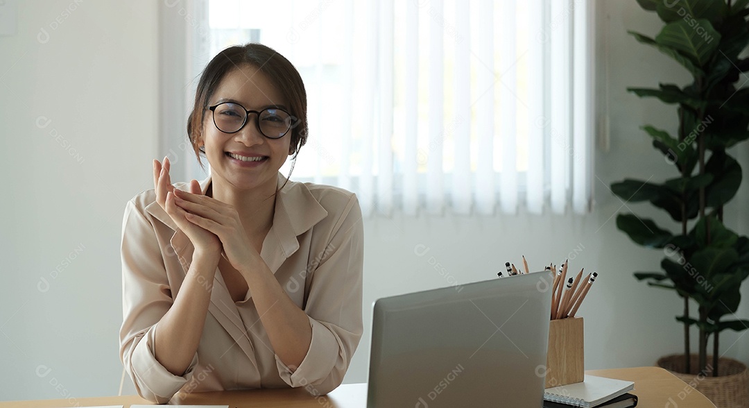 Retrato de uma empresária sorridente sentada na mesa do escritório