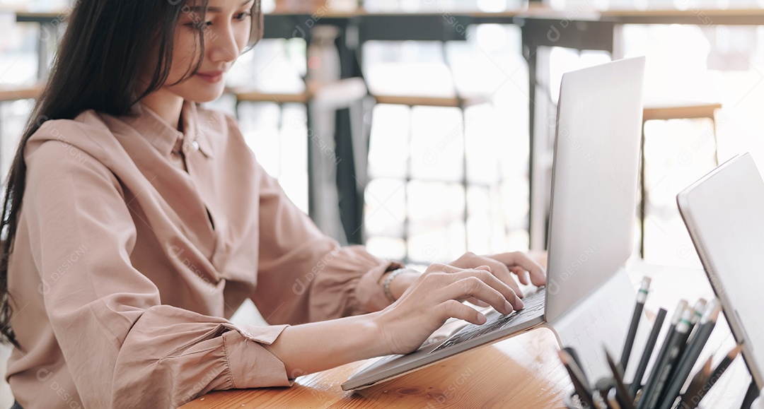 Jovem empresária usando laptop na mesa na oficina