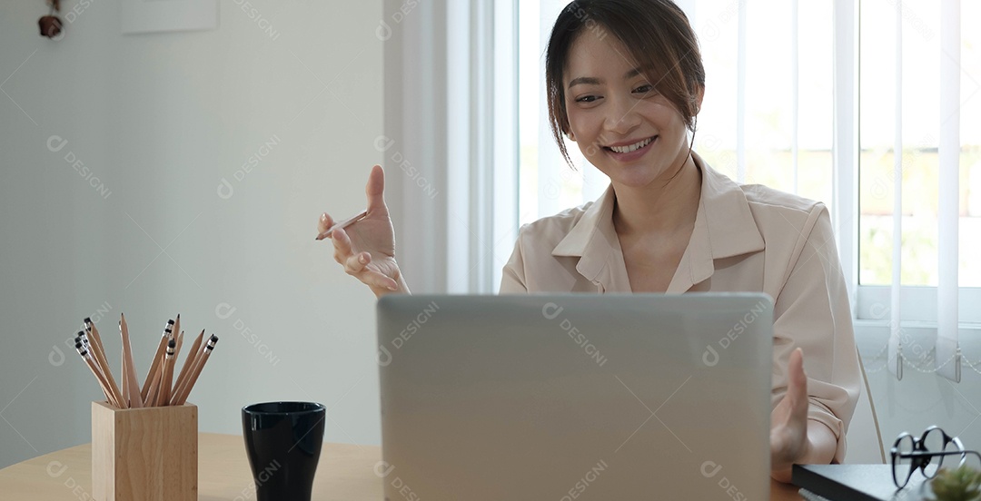 Mulher de negócios asiática sentada feliz trabalhando em seu laptop no escritório.
