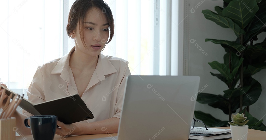Mulher de negócios asiática sentada feliz trabalhando em seu laptop no escritório.