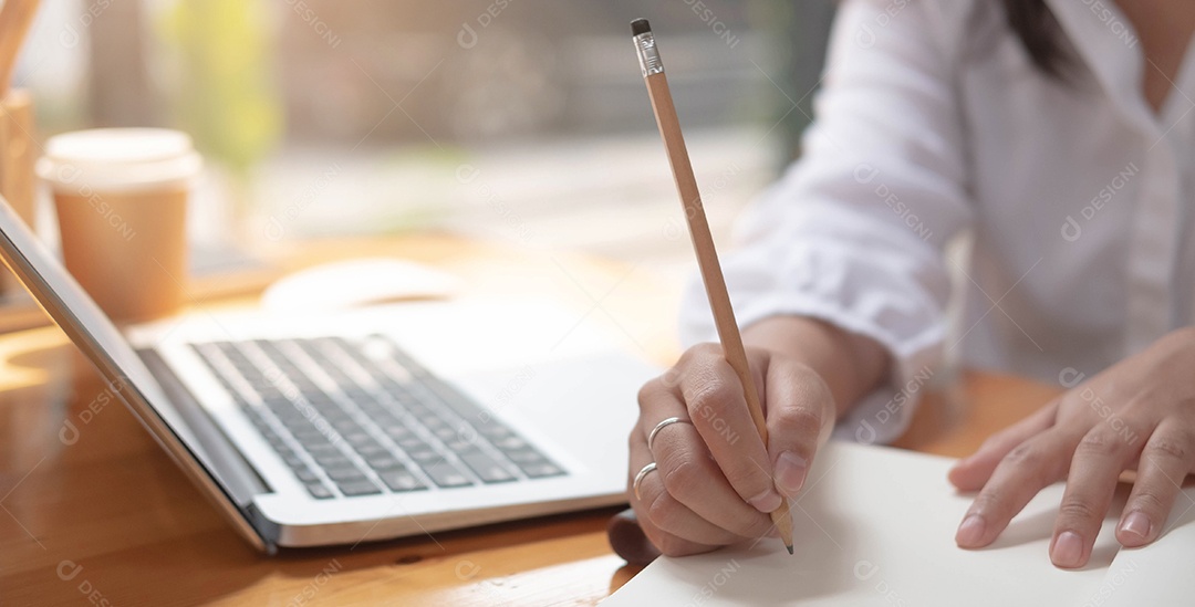 Mão de uma mulher escritora escrevendo em um caderno em casa.