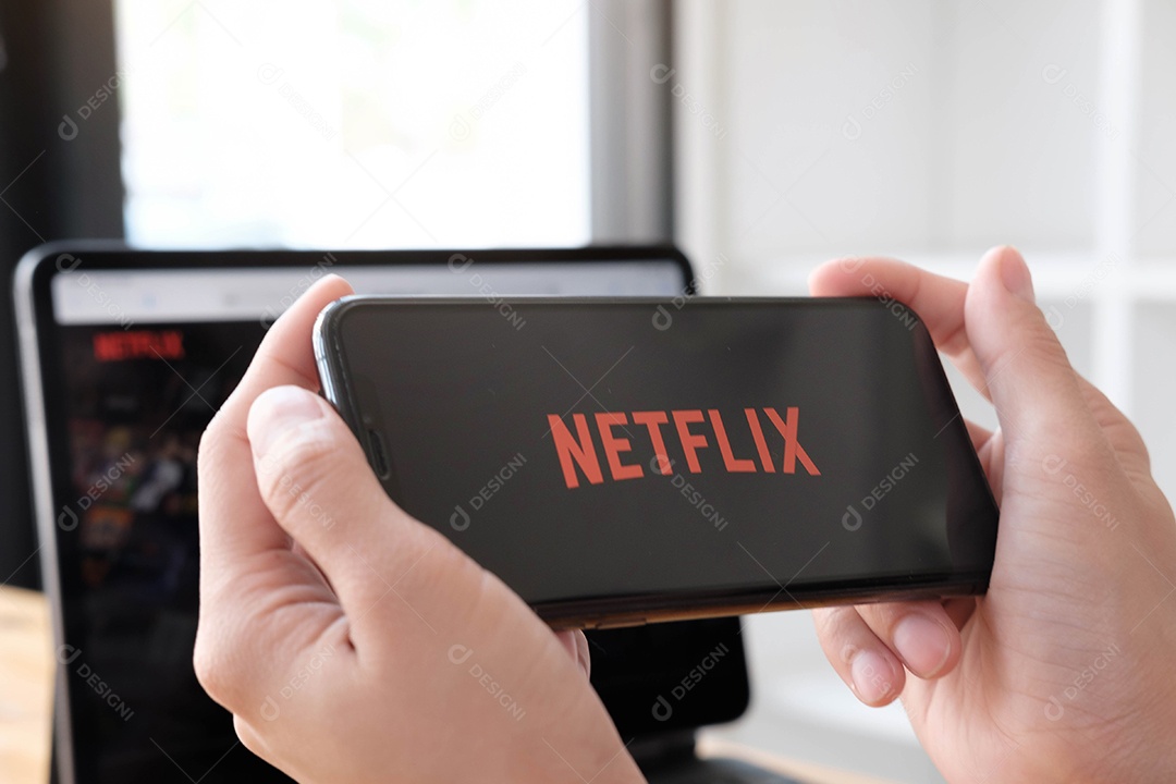 Jovem em uma rede abrindo o Netflix em seu smartphone.