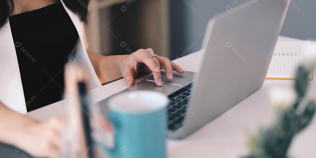 Mão feminina digitando no teclado do computador portátil em casa