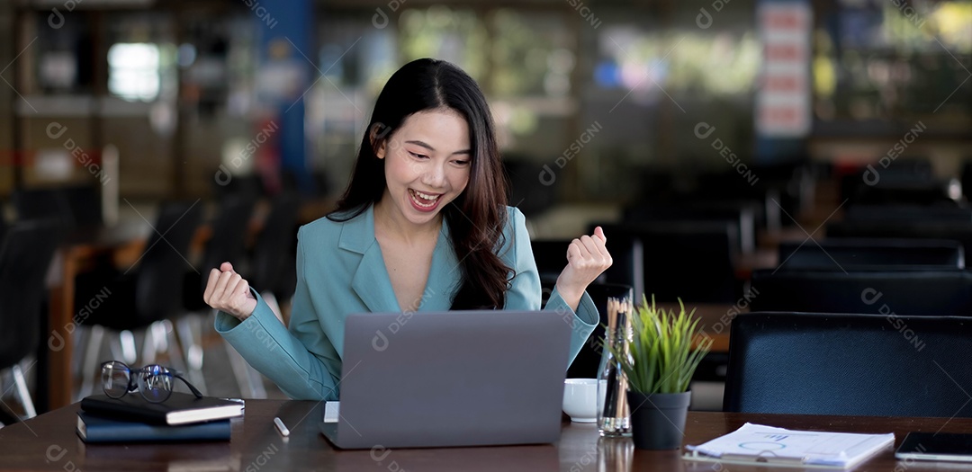 Feliz jovem empresária asiática sentada em seu local de trabalho