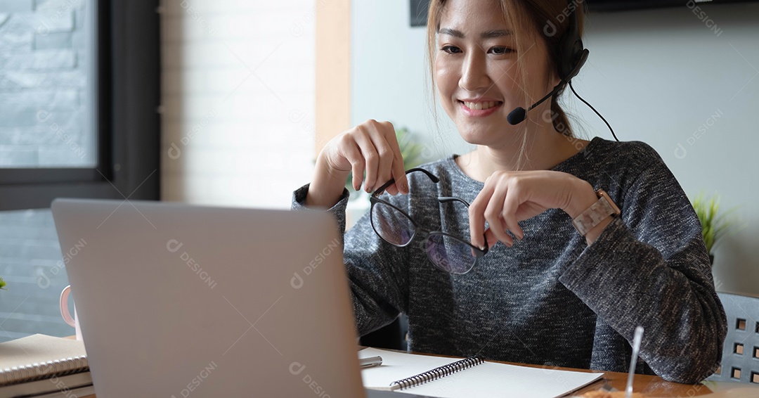 Mulher sorridente asiática freelancer usando fone de ouvido