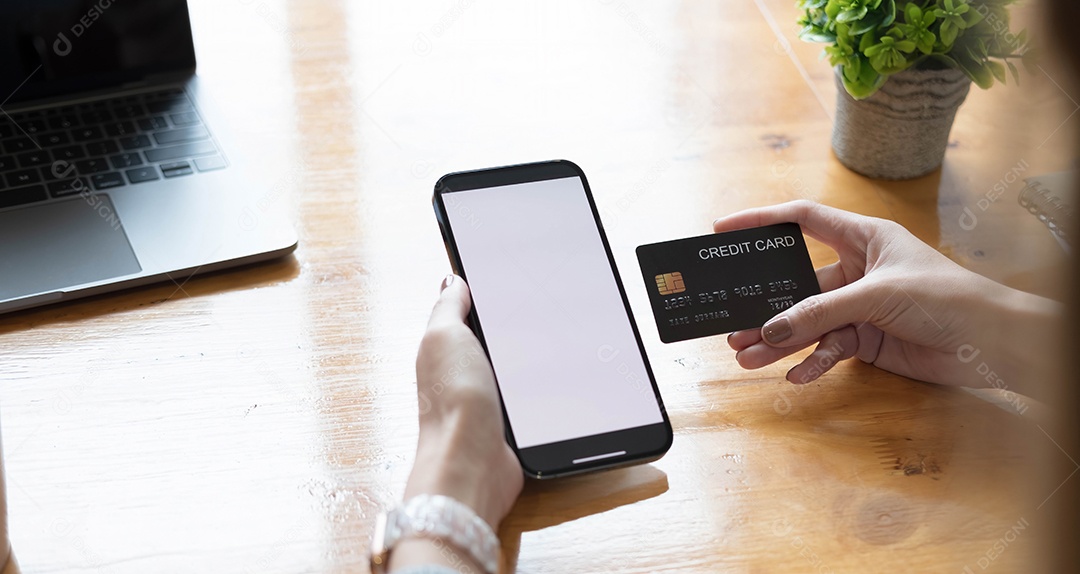 Mãos segurando telefone celular e cartão de crédito com tela de espaço de cópia em branco