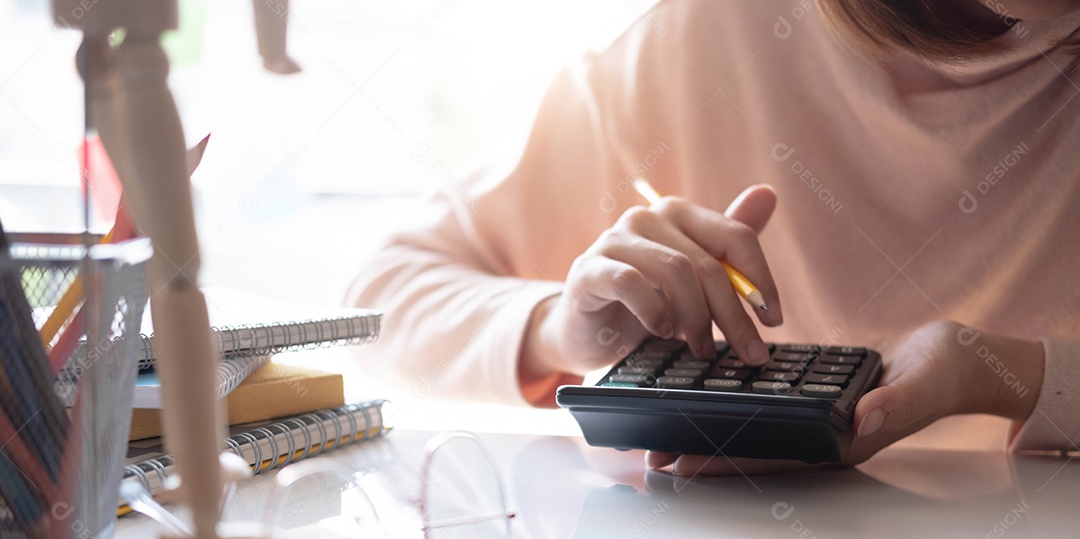 Mão de mulher trabalhando com calculadora e segurando de lápis amarelo
