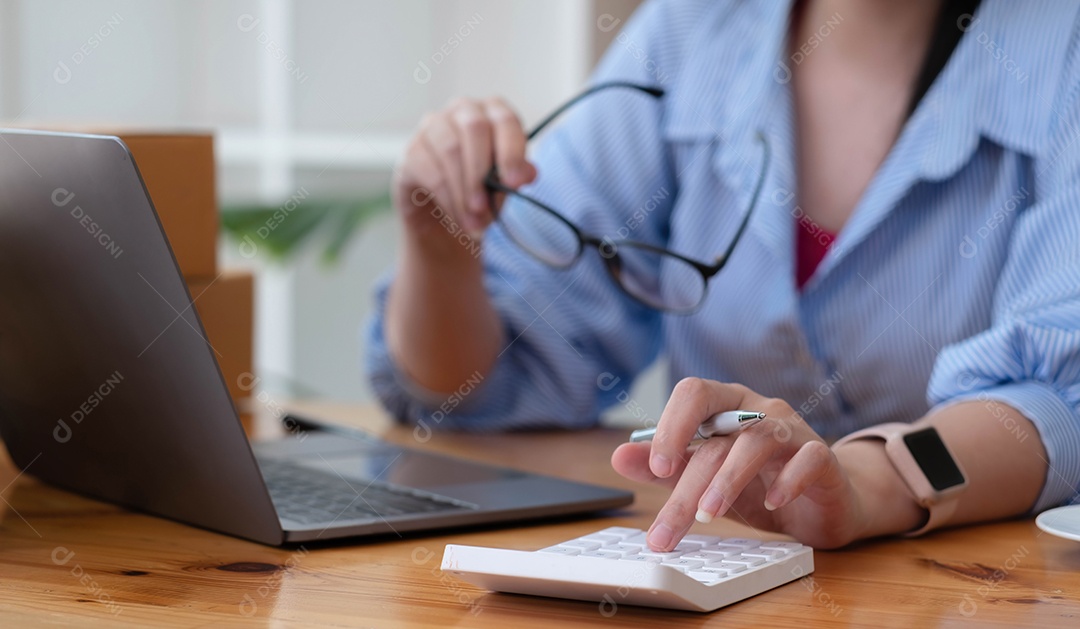 Mulher de negócios usando calculadora e laptop para fazer matemática