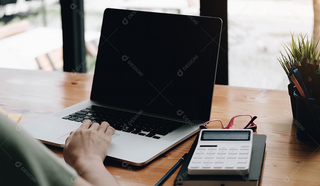 Empresária usando laptop de maquete enquanto trabalha com calculadora