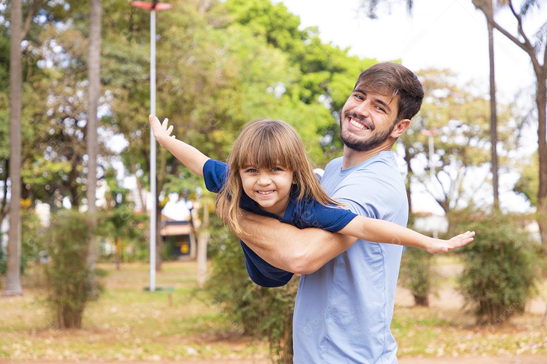 Pai e filha brincando no parque. Feliz Dia dos Pais Pai jogando em um avião com sua filha nos braços