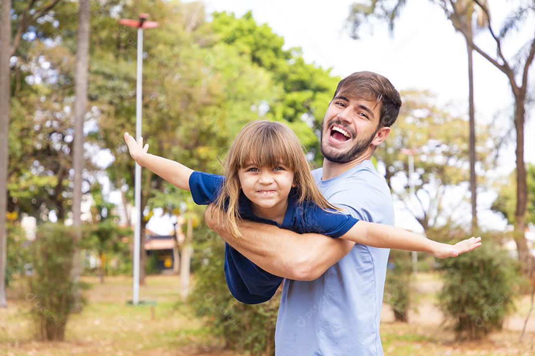 Pai e filha brincando no parque. Feliz Dia dos Pais Pai jogando em um avião com sua filha nos braços