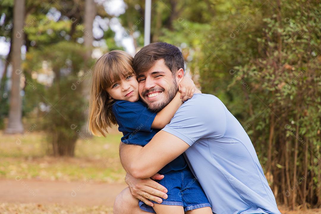 Jovem papai e sua filha se abraçando alegremente no parque. Dia dos Pais