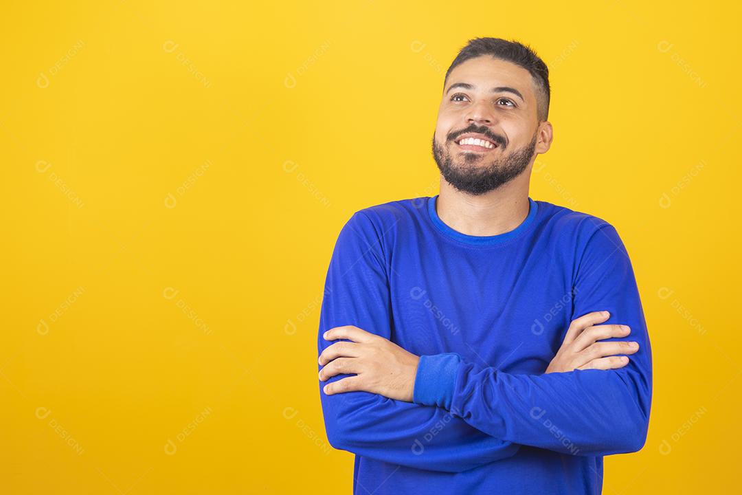 Menino bonito sorrindo olhando para a câmera com os braços cruzados.