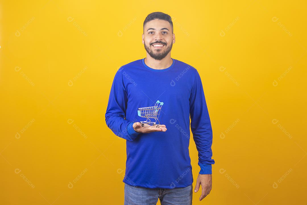Homem jovem segurando um mini carrinho de compras