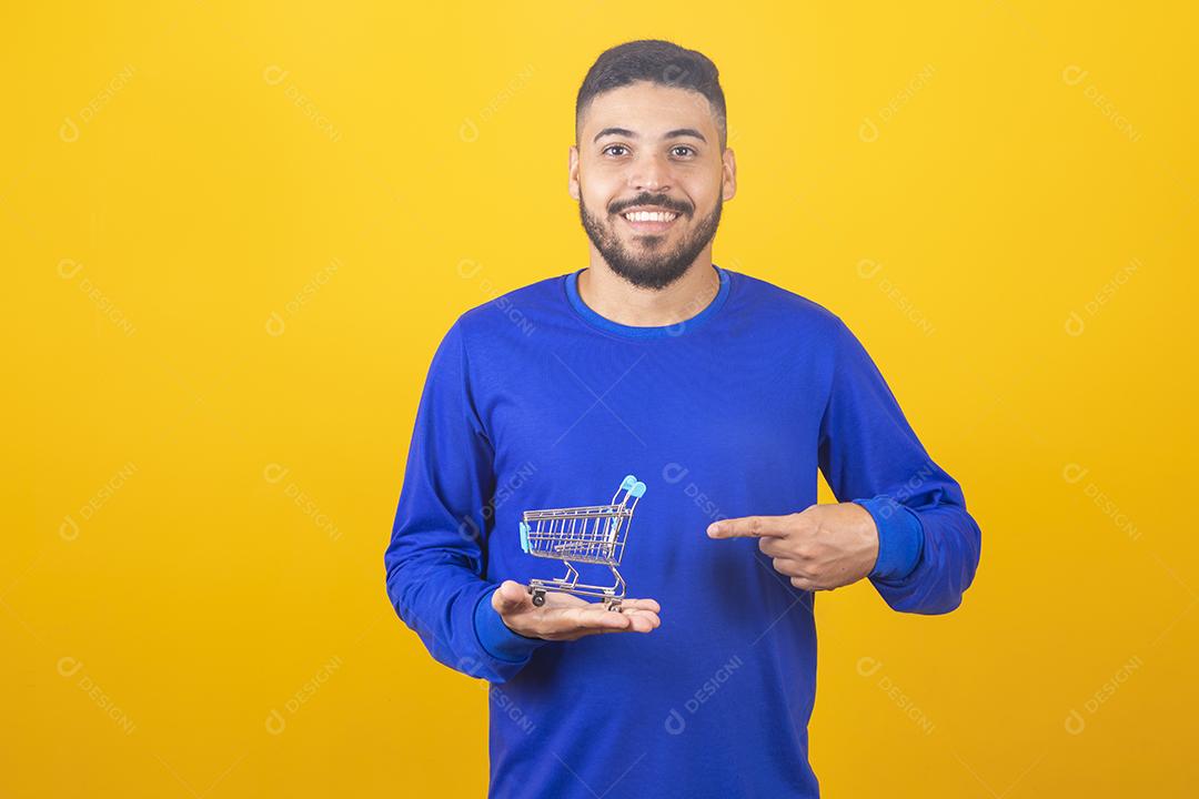 Homem jovem segurando um mini carrinho de compras