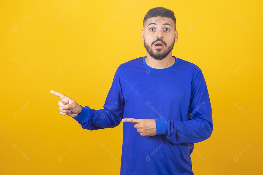 Expressivo jovem rapaz bonito apontando para o lado