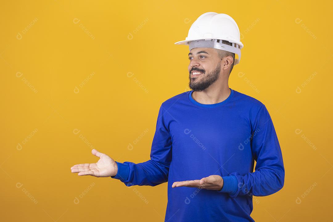 Homem jovem arquiteto com capacete apontando para o lado