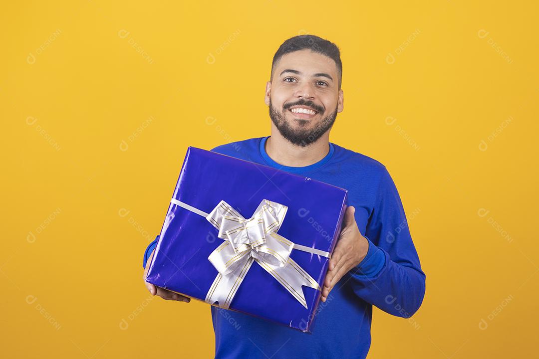 jovem sorridente segurando uma caixa de presente em fundo amarelo jovem segurando uma caixa de presente em fundo amarelo