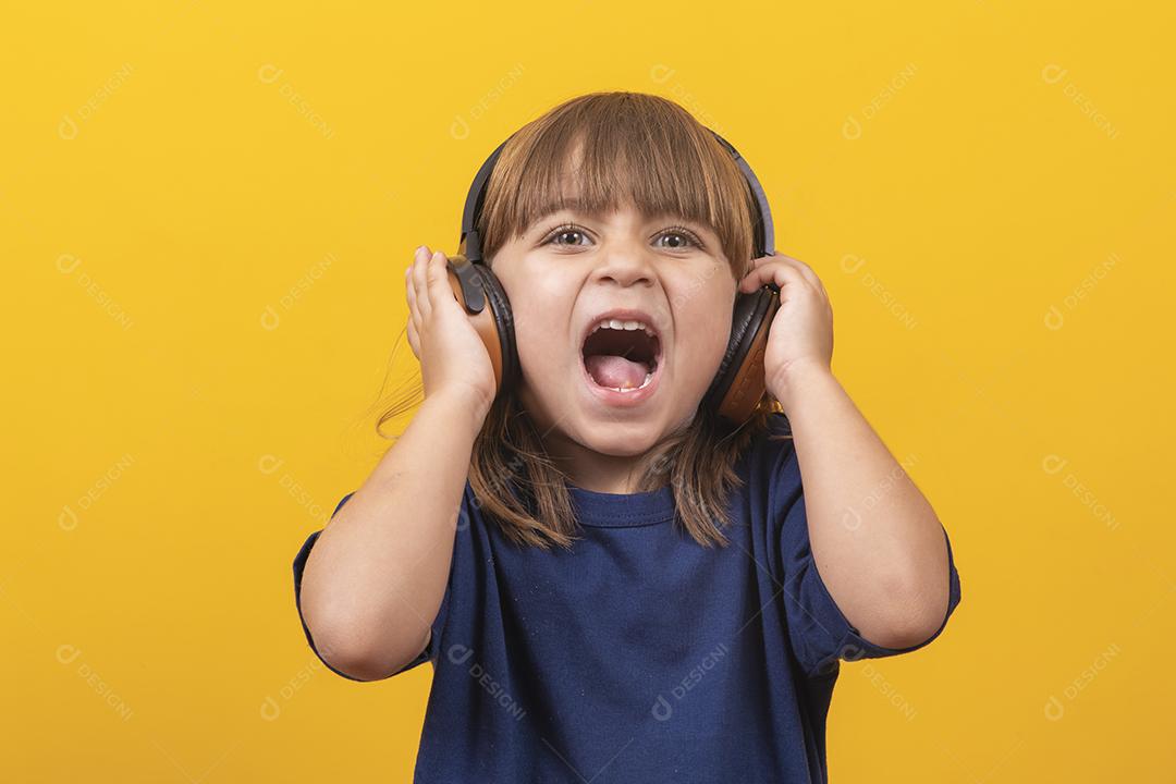 menina caucasiana bonitinha com fones de ouvido ouvindo música em fundo amarelo