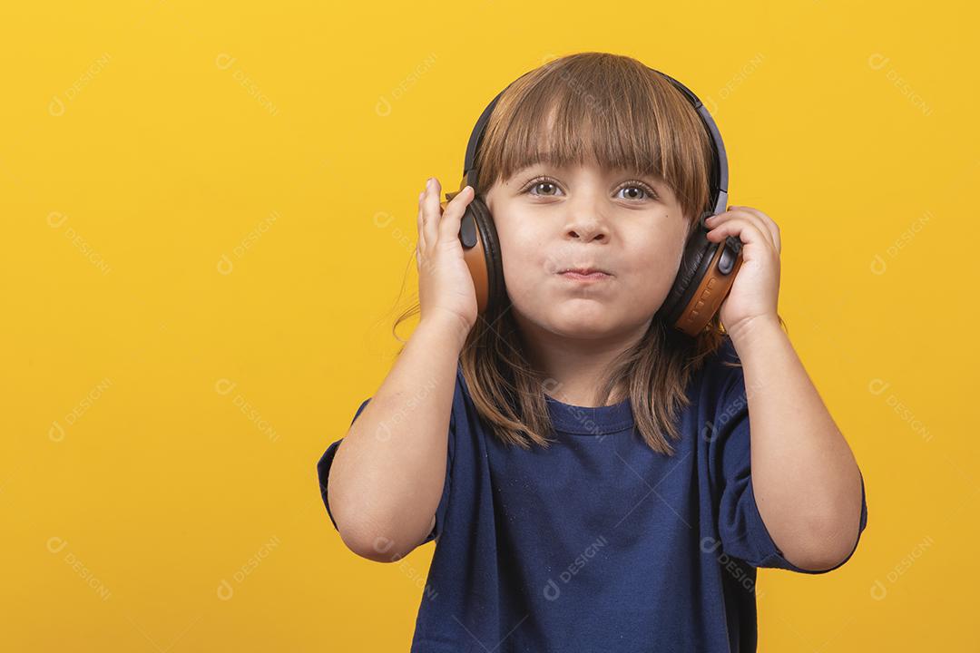 menina caucasiana bonitinha com fones de ouvido ouvindo música em fundo amarelo
