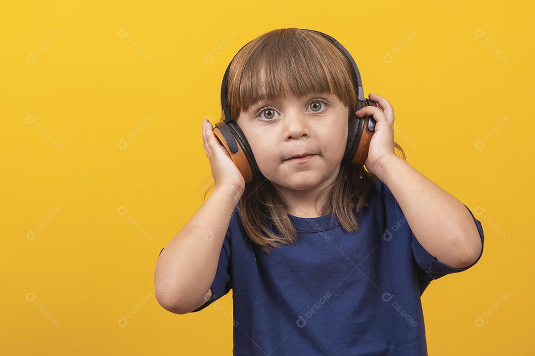 menina caucasiana bonitinha com fones de ouvido ouvindo música em fundo amarelo