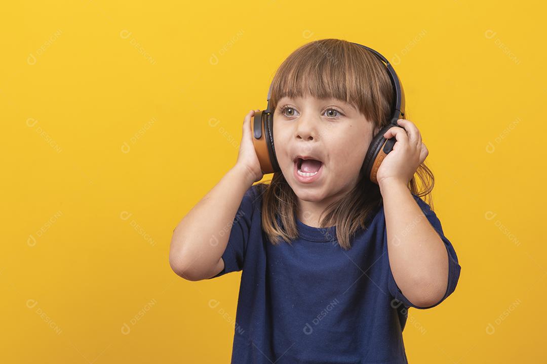 menina caucasiana bonitinha com fones de ouvido ouvindo música em fundo amarelo