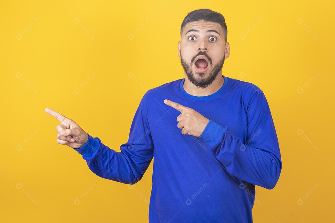 Expressivo jovem rapaz bonito apontando para o lado