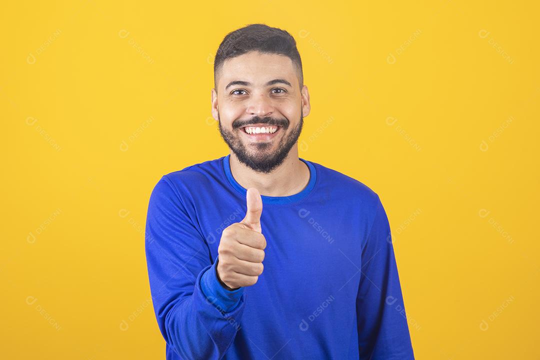 Rapaz bonito em fundo azul, mostrando os polegares