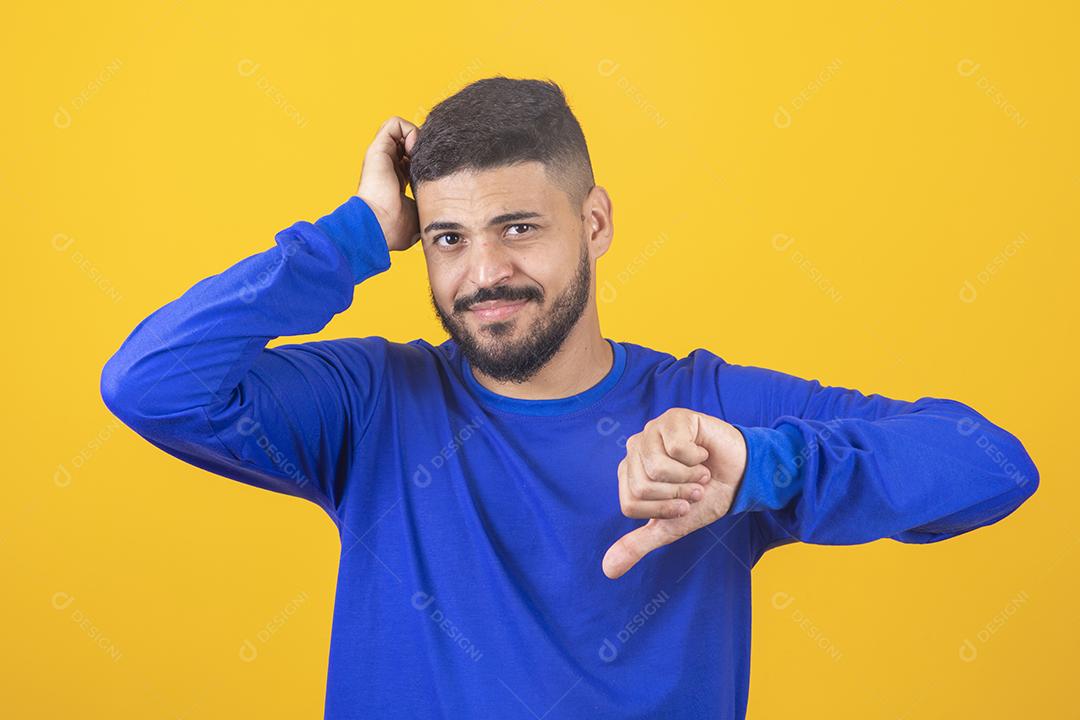 jovem tocando fazendo gesto polegar para baixo em fundo amarelo