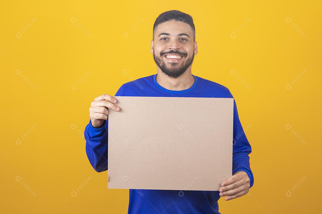 Homem para publicidade. Feliz homem caucasiano apontando para o quadro branco vazio no fundo amarelo do estúdio, maquete