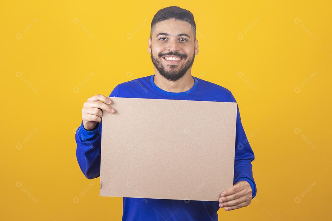 Man for advertising. Happy Caucasian man pointing at empty white board on yellow studio background, mockup