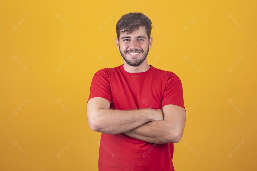Menino bonito sorrindo olhando para a câmera com os braços cruzados.