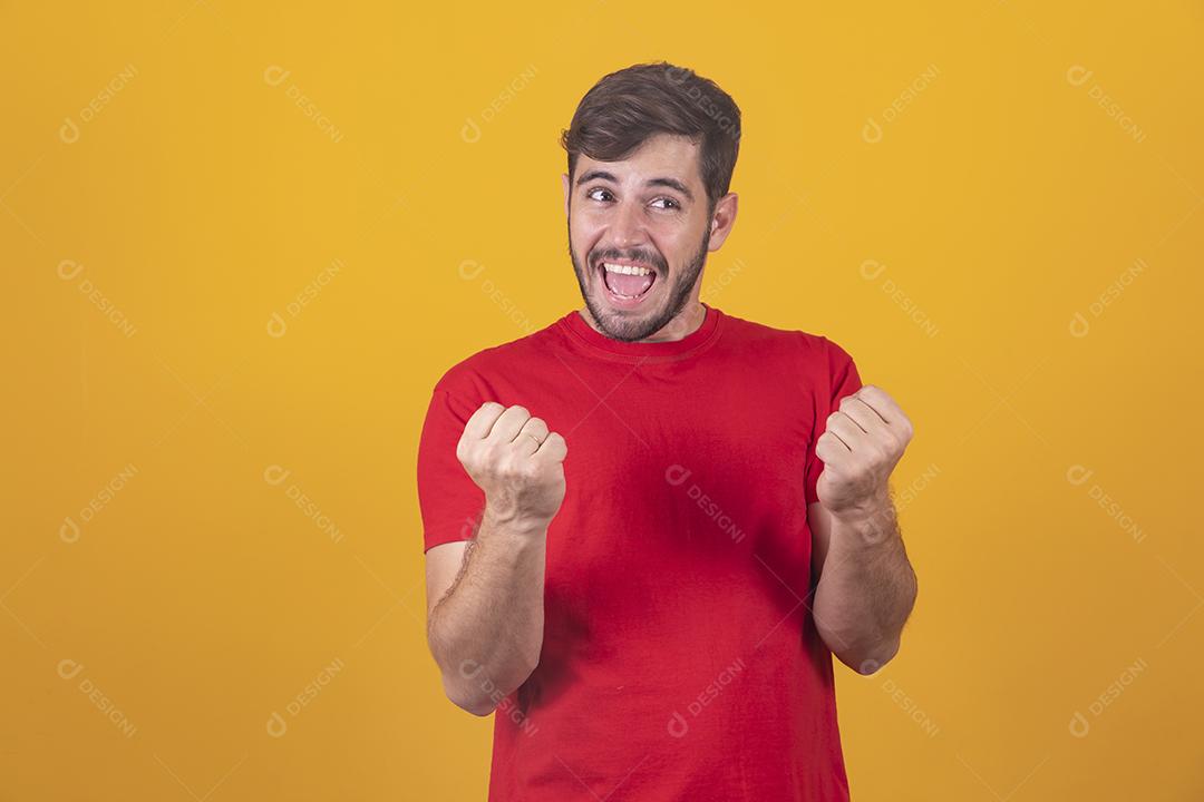 jovem comemorando a vitória sobre fundo amarelo